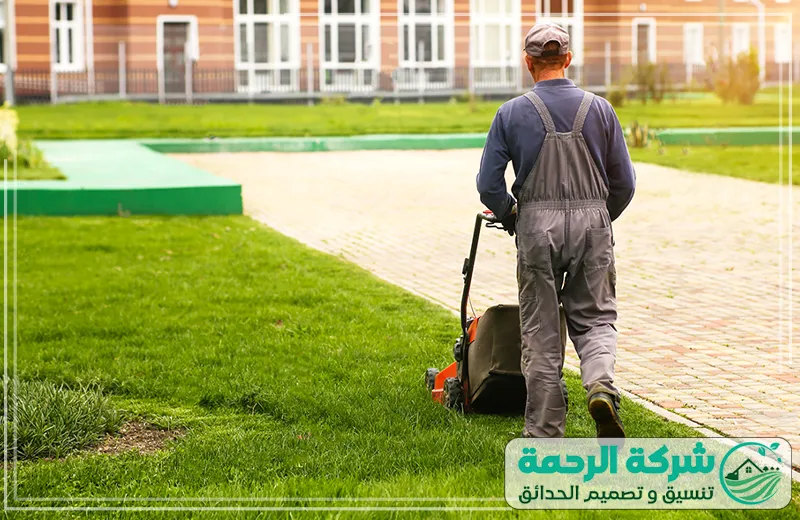 شركة تنسيق حدائق جازان جز العشب وترتيب الحدائق 0559460943 شركة الرحمة تنسيق حدائق جازان عامل يقوم باستخدام آلة جز العشب في حديقة مرتبة لتحسين مظهرها.