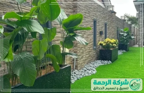 تزيين الحدائق في أبها 0559460943 شركة الرحمة ممر جانبي يبرز روعة التكسيات الحجرية للجدران مع أحواض زرع سوداء فاخرة.